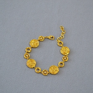 Detail of vintage gold-plated brass bracelet with embossed rose pendants and crystals