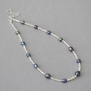 Macro detail of dark baroque pearls and silver faceted beads with lobster clasp and chain