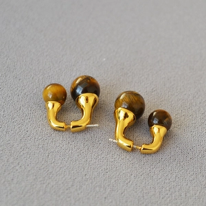 Detail of dual tiger eye beads on golden metal earrings with natural cat eye effect