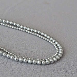 Close-up of elegant double-layered faux pearl necklace with metallic luster on soft fabric