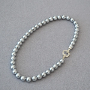 Macro view of high-luster grey pearl necklace with a shimmering round crystal clasp