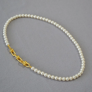Détail du collier de perles avec maillons en forme de U dorés au style industriel chic