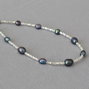 Detail of dark baroque pearls with peacock luster and faceted silver beads on a necklace
