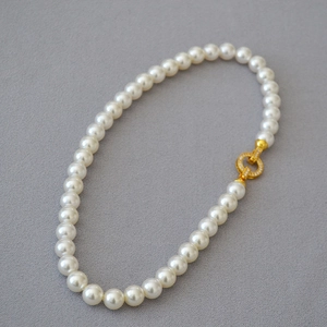 Detail of white pearl necklace with gold clasp paved in sparkling cubic zirconia