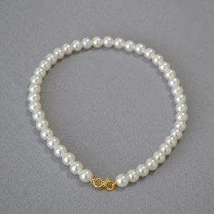 Detail of high-gloss round pearl necklace with elegant gold S-shaped metal clasp closure