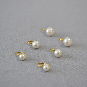 Détail de six boucles d'oreilles perles blanches rondes avec crochets dorés élégants