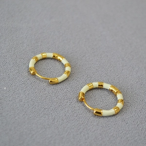 Detail view of gold-plated hoop earrings with cream enamel segments and latch back closure