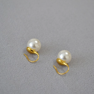 Détail de boucles d'oreilles perles blanches rondes avec crochets dorés élégants