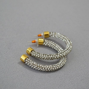 Close-up of gold-plated C-shaped earrings encrusted with sparkling white cubic zirconia