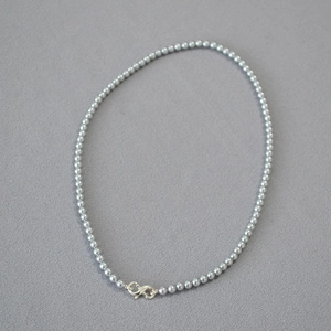 Detail of silver-grey pearl necklace with a unique figure-eight metal clasp