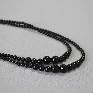 Detail of elegant black onyx beaded necklace with glossy gradient pearls and layers