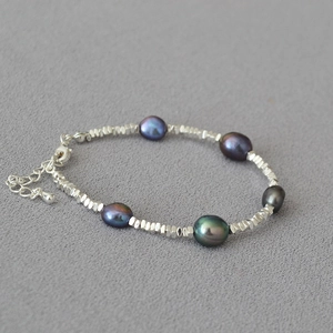 Detailed macro view of dark Tahitian style pearls and faceted silver beads with lobster clasp