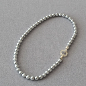Detailed view of silver grey pearl necklace with a gold-tone rhinestone circle clasp
