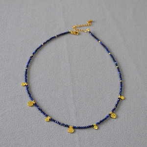 Détail du collier en perles de lapis-lazuli avec pendentifs pièces dorées et fermoir mousqueton