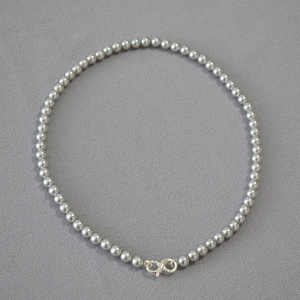 Detail of dark grey pearl necklace featuring a silver infinity shaped lobster clasp