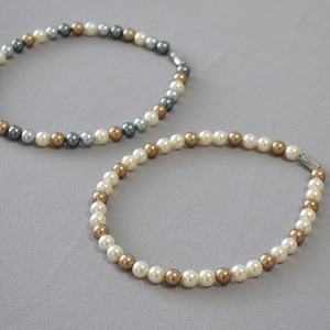 Detail of round faux pearls in champagne, grey and white with silver metal clasps