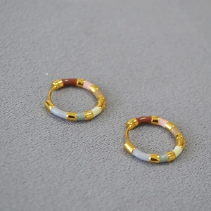 Detail of gold-plated hoop earrings with colorful enamel segments in various pastel tones