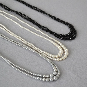 Detailed view of layered pearl necklaces in black, cream white and metallic silver grey