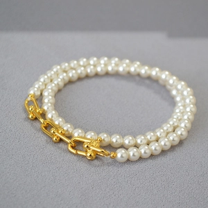 Détail du fermoir en U doré élégant et de la texture du collier de perles lustrées