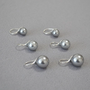 Close-up of grey high-gloss pearls with silver hooks showing smooth metallic luster
