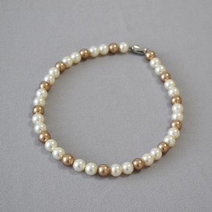 Detail of cream white and champagne gold pearls with silver buckle on textured background