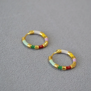 Detail of colorful enamel segments on gold-plated brass hoop earrings with lever-back