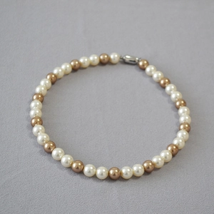Detail of vintage round pearl necklace with white and brown pearls and silver metal clasp