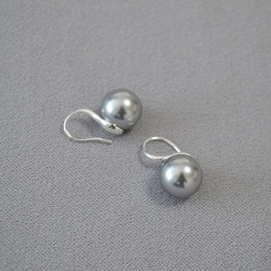 Detailed close-up of dark grey round pearl earrings with silver curved hook hardware