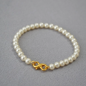Close-up of elegant round cream pearls with a polished gold lobster clasp detail