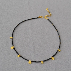 Gros plan du collier bohème avec des perles noires facettées et des breloques dorées