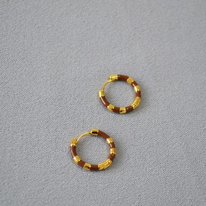 Detailed shot of striped gold-plated brass hoops with dark brown enamel inlay finish