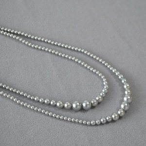 Detail of double-layer grey gradient pearl necklace on soft fabric background