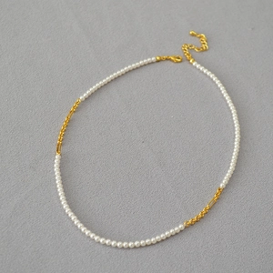 Detail of elegant gold-plated chain necklace with white pearls and adjustable clasp