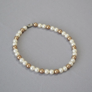 Close-up of white and champagne pearl necklace with silver cylindrical metal clasp