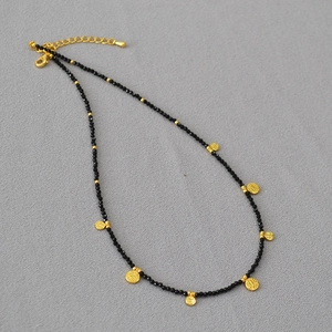 Détail du collier de perles noires avec pendentifs pièces dorées et fermoir