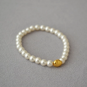 Detail of baroque pearl bracelet with a central gold nugget bead on an elastic cord