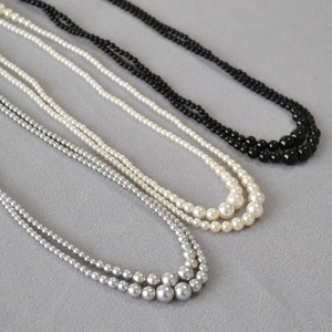Detailed view of layered faux pearl necklaces in white, black and silver gradient colors