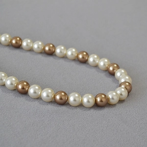 Macro shot of two-tone cream and champagne gold pearls on a luxury necklace