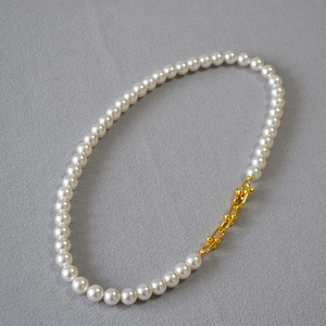 Détail d'un collier de perles élégant avec fermoir à maillons en U doré chic