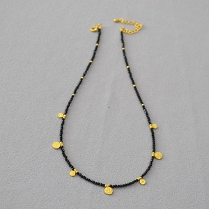 Détail du collier à perles avec pendentifs de pièces martelées en or et perles noires