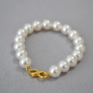 Close-up of high-luster round white pearls with a golden S-shaped metal clasp