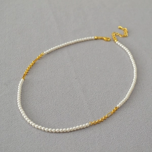 Detail of gold-plated chain necklace featuring small white pearls and adjustable lobster clasp