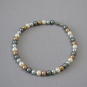 Detail of colorful round pearl necklace featuring mixed cream, gold and grey luster beads