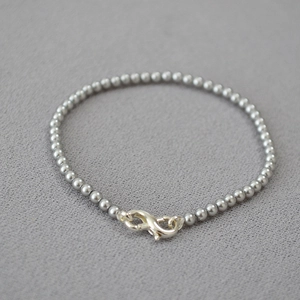 Detail of the infinity symbol clasp on a minimalist silver beaded bracelet
