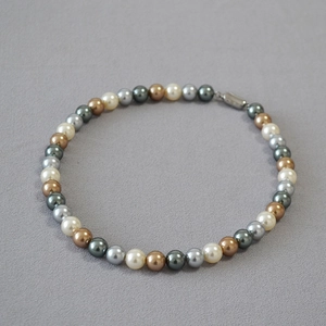 Macro view of multi-color round pearls in silver grey, bronze and dark grey with magnetic clasp