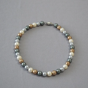 Detail view of round multicolor faux pearls in neutral tones with a silver metal clasp