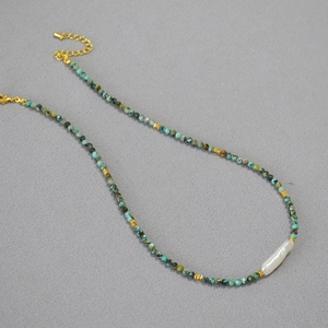 Detailed macro view of irregular turquoise beads with a white baroque pearl and golden clasp