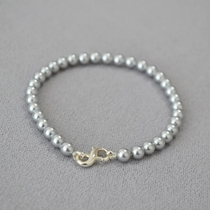 Detail of gray imitation pearls and gold infinity clasp on an elegant beaded bracelet