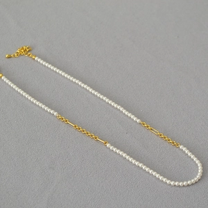 Detail of elegant gold-plated chain necklace with white pearls and lobster clasp