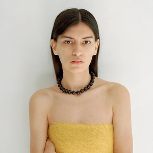 Detail of chunky black agate beaded necklace with high-gloss finish on a model